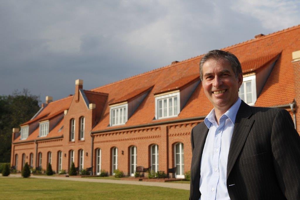 Bert Groche lacht vor dem Backsteingebäude des Schlosswirts Meseberg